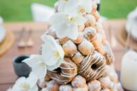 20 a cool croquembouche wedding cake with glazed donuts and fresh white blooms is a cool take on a classic croquembouch