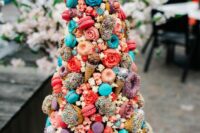 21 a crazy and super colorful wedding cake topped with a croquembouche of turquoise and coral macarons, glazed donuts, ice cream cones and candies is wow