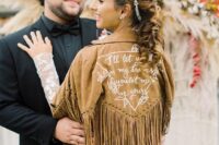 21 a tan suede bridal jacket with white calligraphy and sutds plus long fringe is a perfect addition to a boho bridal look
