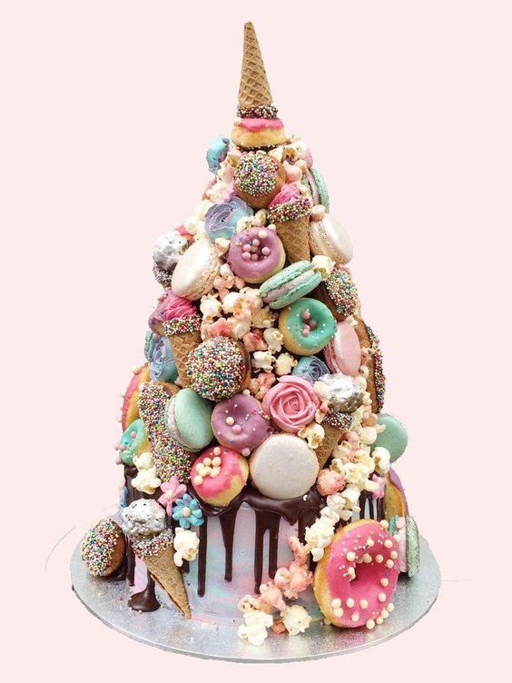 a quirky colorful wedding cake with chocolate drip, mint, neutral and mauve glazed donuts and macarons, candies, sugar blooms and ice cream cones