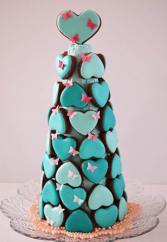 a quirky glazed heart-shaped cookie tower with pink sugar butterfies is a very catchy and bold idea