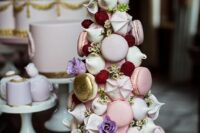 29 a chic and refined tower wedding cake that consists of pink and neutral macarons, meringues, gilded macarons, lilac blooms and meringues