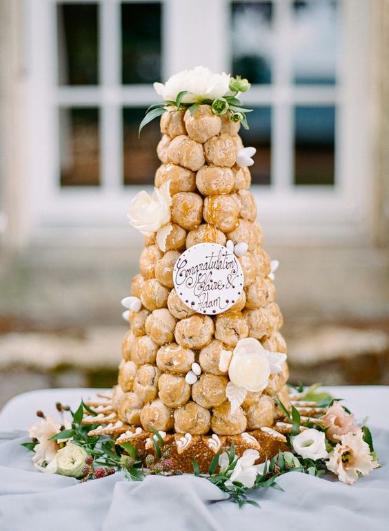 a beautiful and delicious croquembouche decorated with sugar and fresh blooms, topped with a bloom and with sugar calligraphy decor