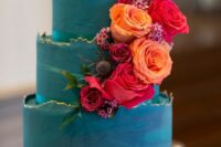 a beautiful teal wedding cake with a gilded edge, bold orange and red roses, thistles and greenery will be amazing for a jewel-tone wedding