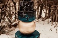a black and teal celestial wedding cake with white constellations, with a gold sphere in between and a half moon cake topper