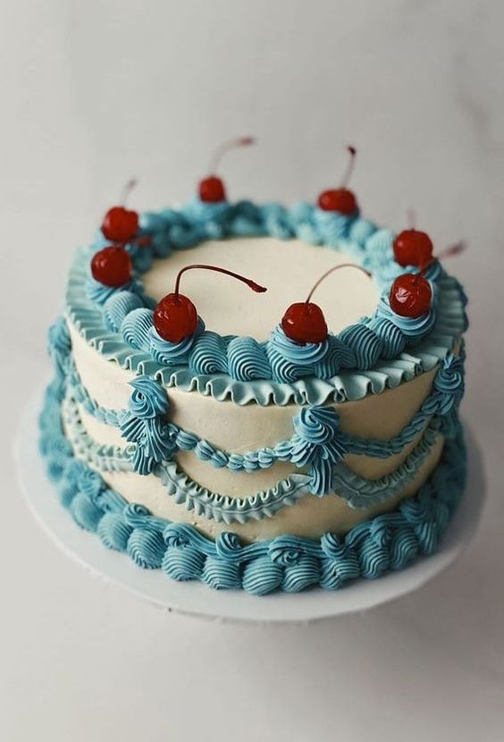 a blue and white lambeth wedding cake topped with cherries is a bright and cool solution for a retro-infused wedding