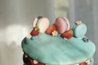 a blue macaron cake with vanilla cream, strawberries and pastel-colored macarons on top is an amazing idea