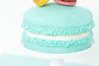 a bold turquoise macaron cake topped with colorful macarons is a lovely and bold idea for a spring or summer wedding