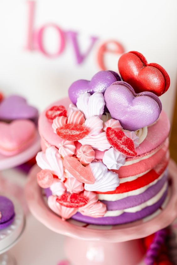 a bright macaron wedding cake in pink, red and purple, with meringues, heart shaped macarons and lip candies