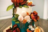 a bright wedding cake with teal and white wedding cake with dripping, orange blooms and greenery and neutral macarons plus a vine heart