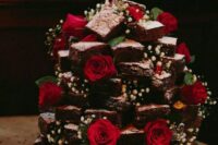 a brownie stack decorated with baby’s breath, greenery and red roses is a cool rustic wedding idea