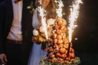 a caramel croquembouche decorated with a bit of blooms and sparklers is a lovely idea for a wedding