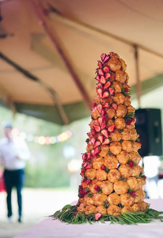 a catchy wedding croquembouche decorated with greenery and fresh strawberries is amazing for a summer wedding