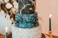 a celestial wedding cake with a silver tier, a teal textural one, a black tier with silver decor and a silver sphere on top