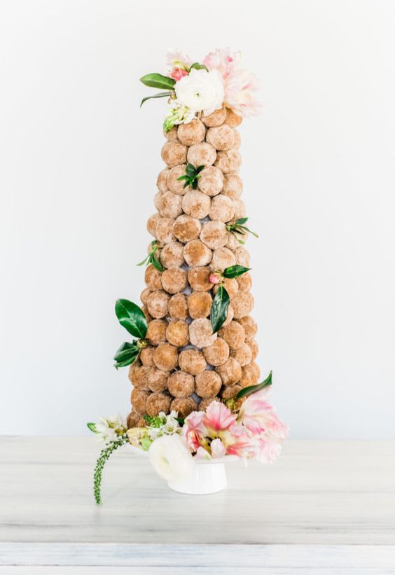 a chic and lovely croquembouche decorated with pink and white blooms and greenery plus sugar icing is amazing