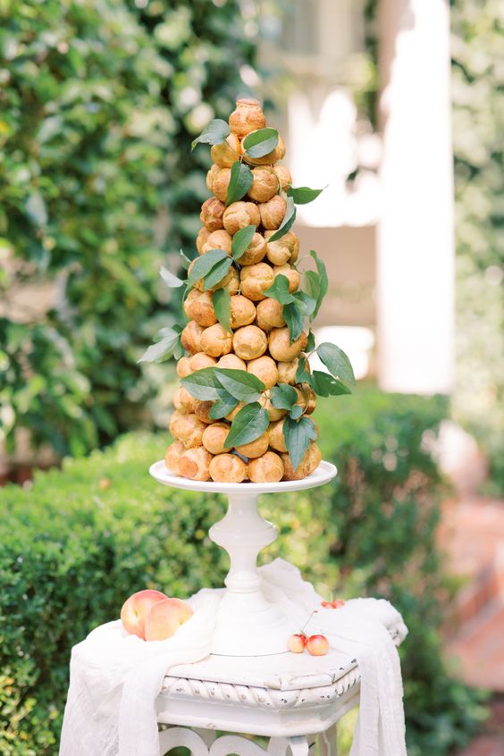 a chic and sophisticated croquembouche decorated with greenery is a great wedding cake alternative