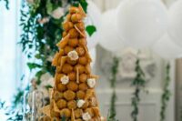 a chic croquembouche with cookie shards and white blooms is a stylish and refined idea for a garden wedding