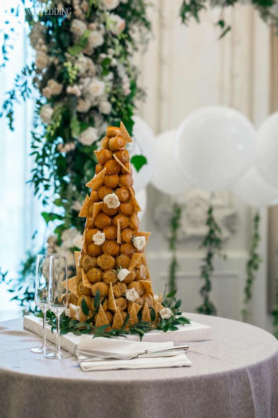 a chic croquembouche with cookie shards and white blooms is a stylish and refined idea for a garden wedding