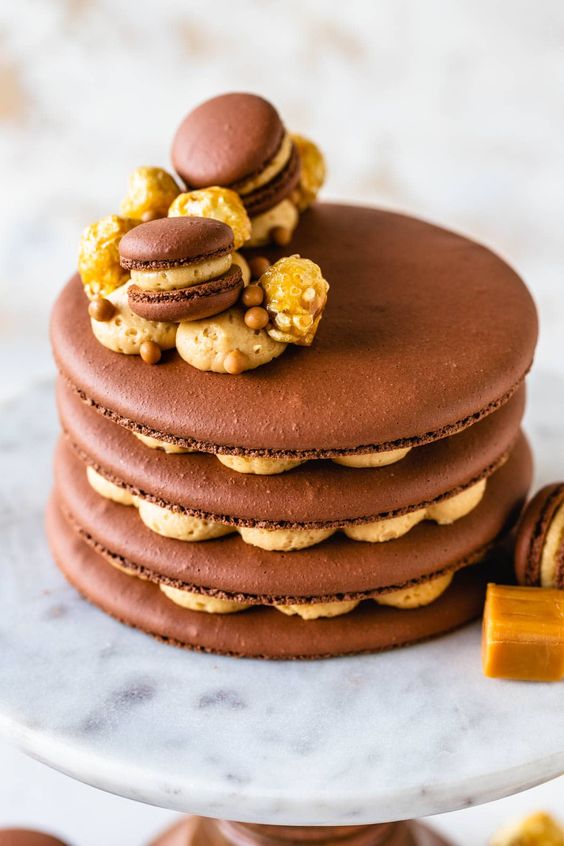 a chocolate caramel macaron cake topped with macarons and nuts is a stylish and cool idea for a modern wedding