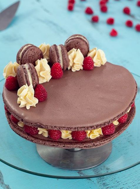 a chocolate macaron cake with vanilla, raspberries and mini chocolate macarons on top is amazing and delicious