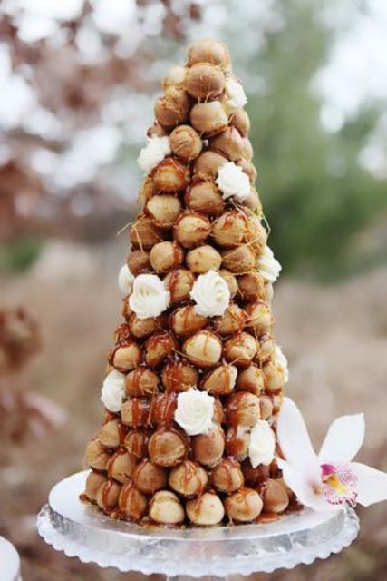 a classic croqeumbouche with caramel drip and icing, white blooms is a stylish idea for a modern wedding