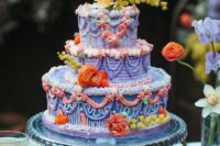 a colorful lambeth wedding cake done in purple, lilac, turquoise, orange and topped with bright orange and yellow blooms