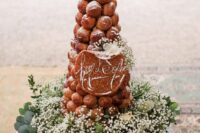 a croquembouche decorated with caramel and sugar powder, white baby’s breath and a calligraphy topper