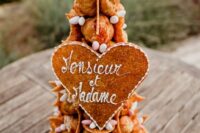 a croquembouche topped with candies and sugar powder, with a cookie cake topper for a spring wedding