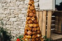 a croquembouche with pistachio cream served on a wooden slice with fresh flowers