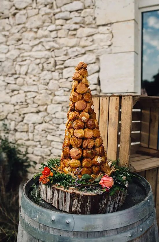 a croquembouche with pistachio cream served on a wooden slice with fresh flowers