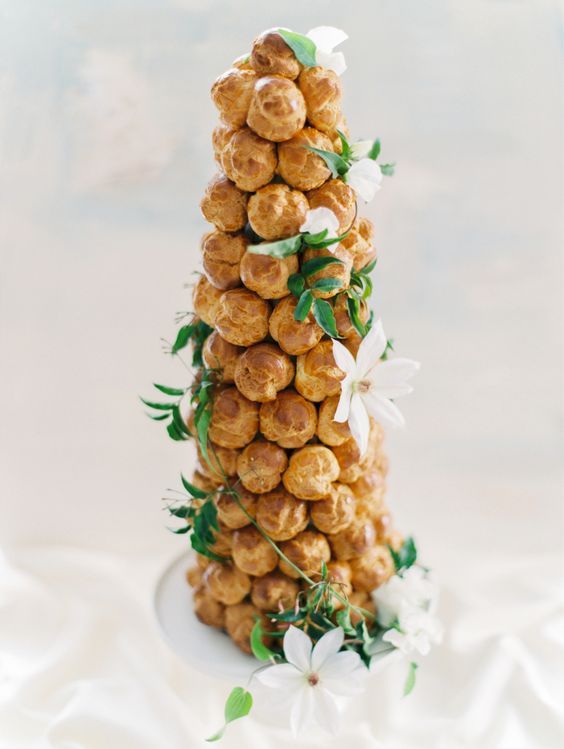 a cute modern croquembouche wedding cake decorated with greenery and white blooms for a modern wedding