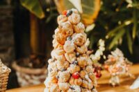 a delicious croquembouche topped with sugar powder, blackberries and strawberries is a great idea for a tropical wedding