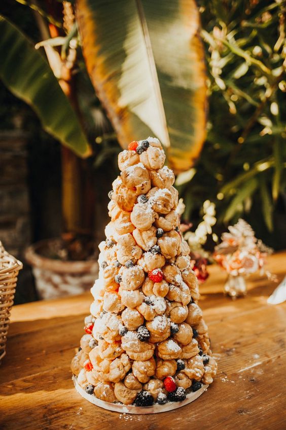 a delicious croquembouche topped with sugar powder, blackberries and strawberries is a great idea for a tropical wedding