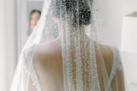 a glam wedding veil with crystals covering the head and going back is a creative take on classic embellished veils