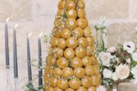 a glazed croquembouche decorated with blush blooms and blooming branches is a beautiful idea for a spring or summer wedding