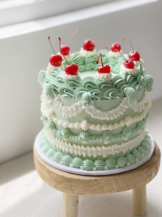 a green and white lambeth wedding cake with lots of sugar patterns and topped with cherries is a fun idea for a spring wedding