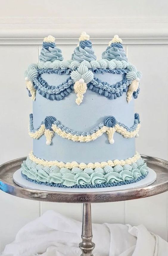 a lambeth wedding cake done in various shades of blue and ivory, with sugar patterns and sugar decor on top is amazing