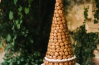 a large and refined croquembouche with caramel icing on top is a stylish idea for a spring or summer wedding