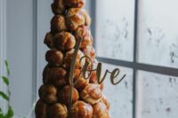 a large croquembouche topped with caramel drip, with a calligraphy topper and a creative caramel topper