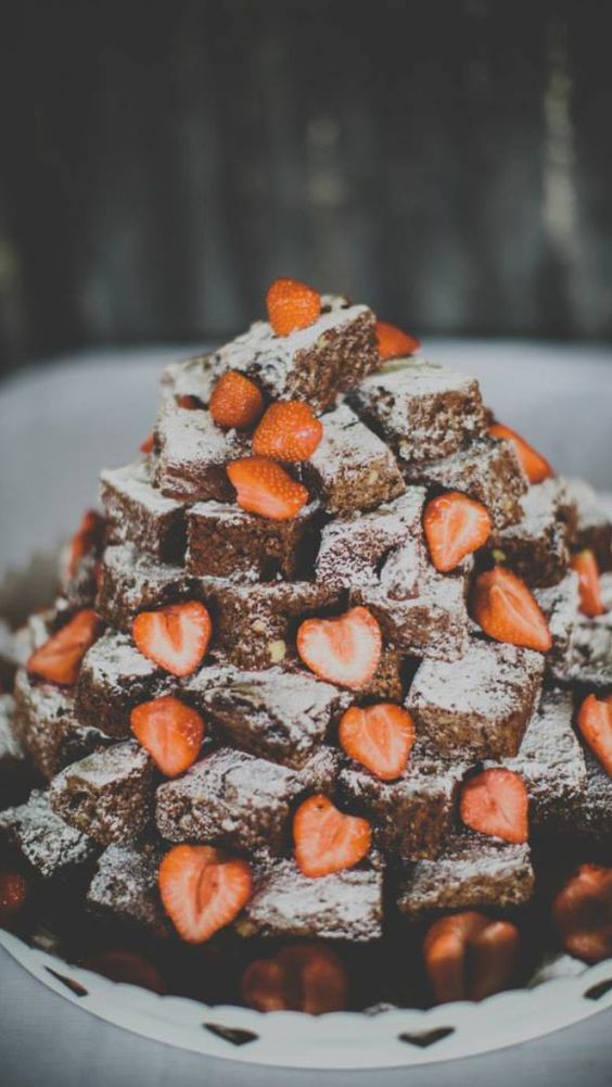 a lovely brownie stack topped with sugar powder and fresh strawberries is a cute idea that looks delicious