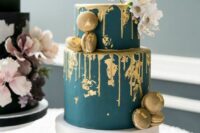 a matte teal wedding cake with gold dripping, gold foil, gold macarons, white blooms on top is a very sophisticated idea