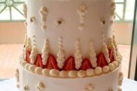 a neutral and ivory lambeth wedding cake decorated with strawberries, stars and a traditional cake topper for a classic wedding