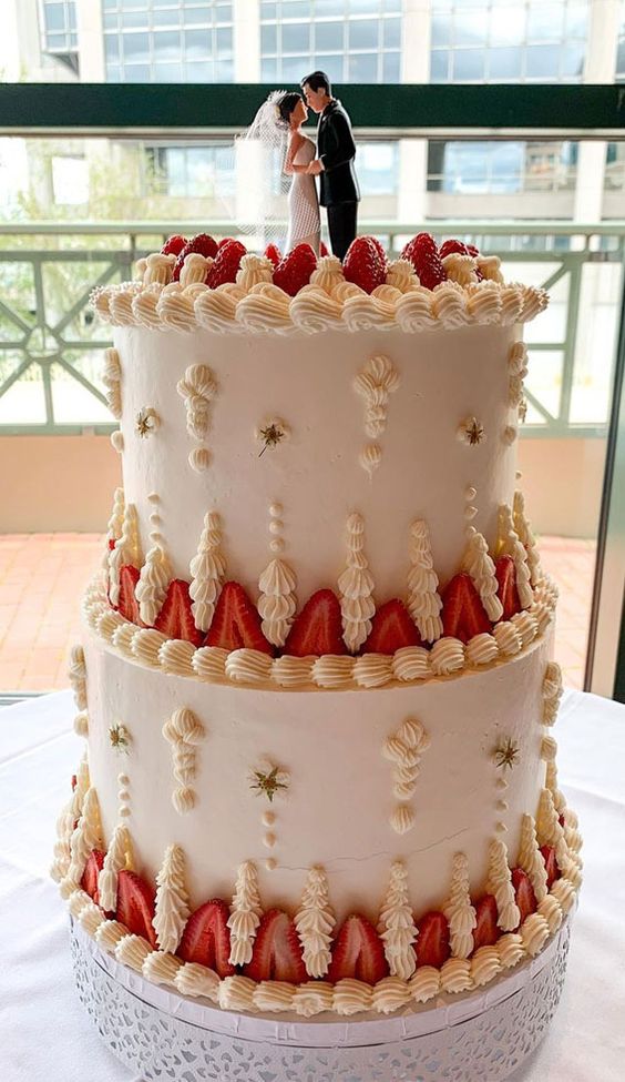 a neutral and ivory lambeth wedding cake decorated with strawberries, stars and a traditional cake topper for a classic wedding
