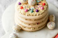 a neutral macaron cake topped with colorful beads and macarons with colorful sprinkles is a lovely idea for a spring or summer wedding