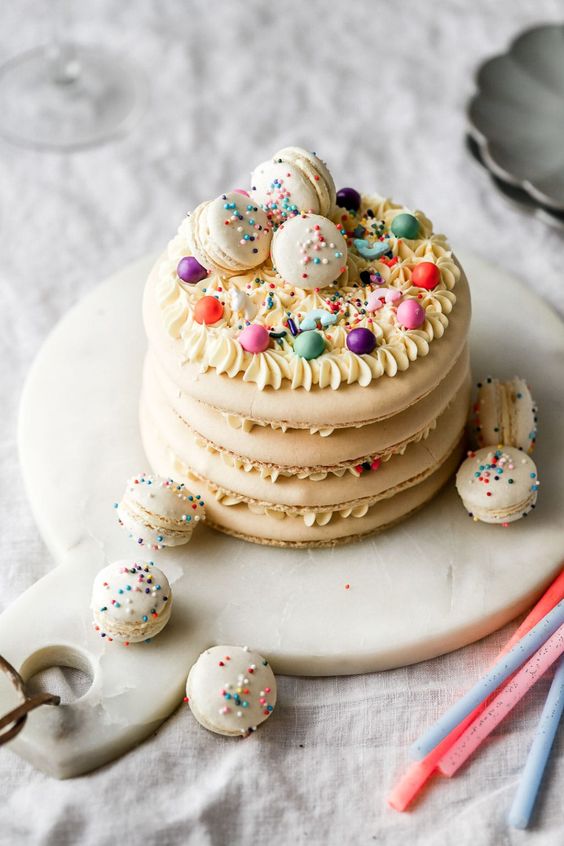 a neutral macaron cake topped with colorful beads and macarons with colorful sprinkles is a lovely idea for a spring or summer wedding