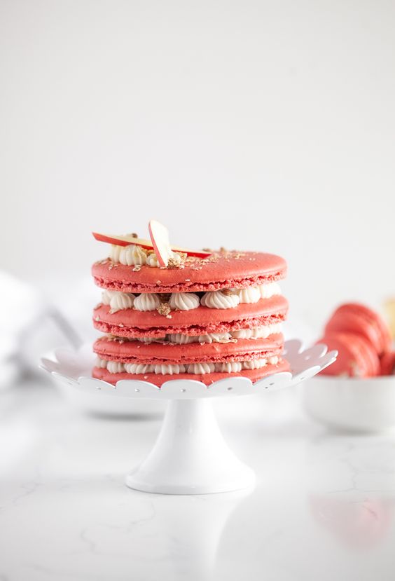 a pink apple macaron cake with vanilla cream and apple slices on top is a lovely idea for a fall wedding