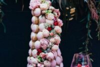 a pink icing croquembouche decorated with pink and red blooms and pink meringues and pink glazed donuts for a wedding