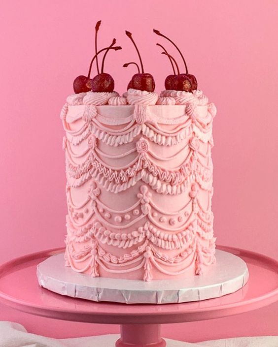 a pink lambeth wedding cake with lovely patterns and cherries on top is a cool idea for a spring or summer wedding