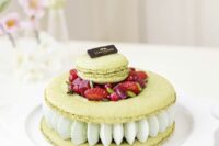 a pistachio macaron cake with cream, fresh strawberries and other berries plus a macaron on top is amazing for a wedding