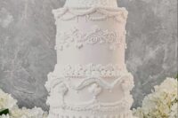 a pure white tall lambeth wedding cake with sugar detailing is an amazing idea for a spring or summer wedding, it looks cool and chic